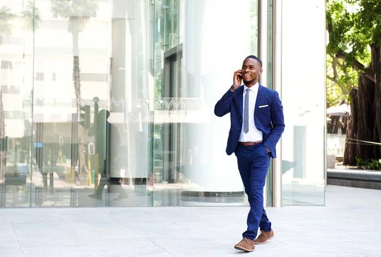 Man walks outside office building while talking on cell phone