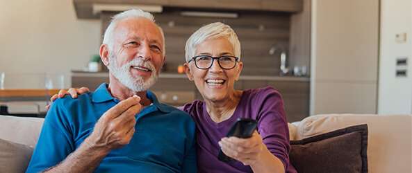 a senior couple watching tv on the couch