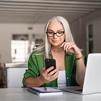 Woman at desk works from home with multiple devices.