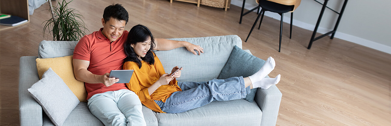 couple looking at their electronics on a couch